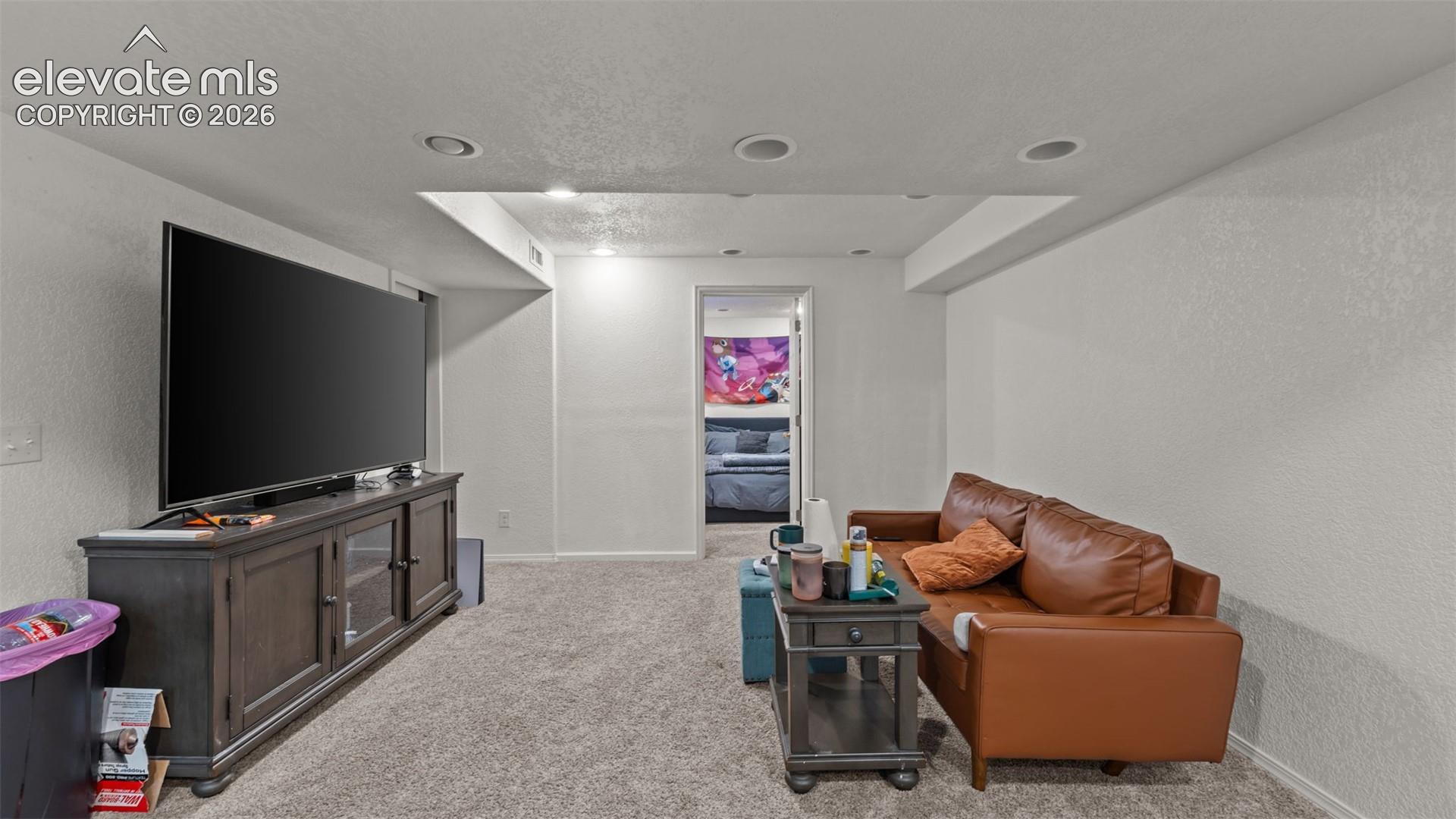 Recessed lighting, textured walls, and carpeting