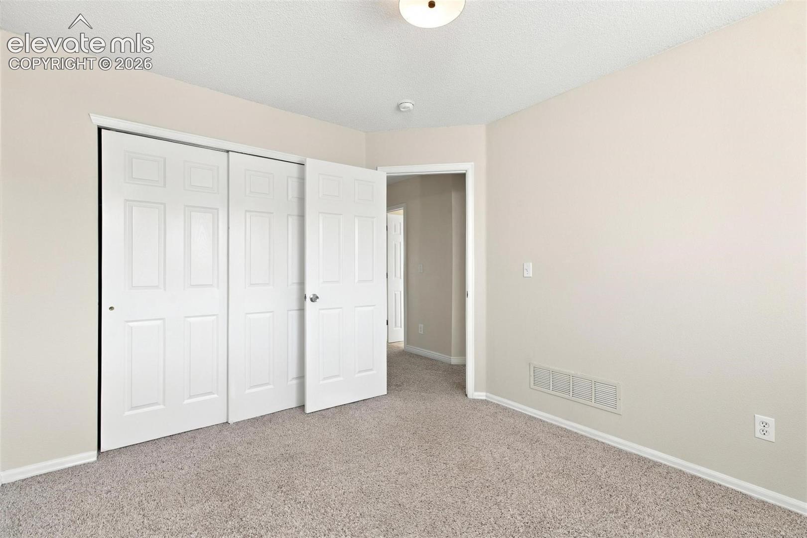 Neutral-toned wall paint, carpeted flooring, and a multi-panel sliding closet door with a white finish
