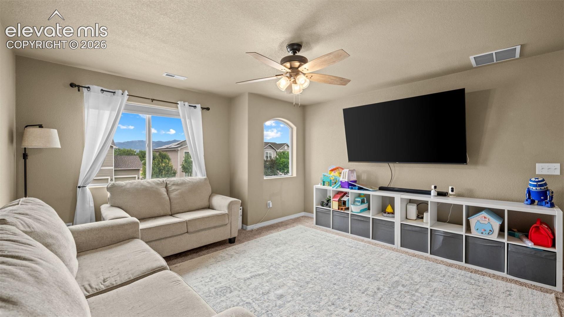 Spacious bonus room featuring a ceiling fan, dual windows, and built-in shelving