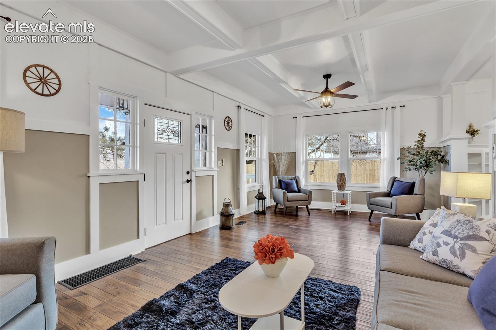 Living area featuring wood-finish flooring, a coffered ceiling, and a ceiling fan with integrated lighting