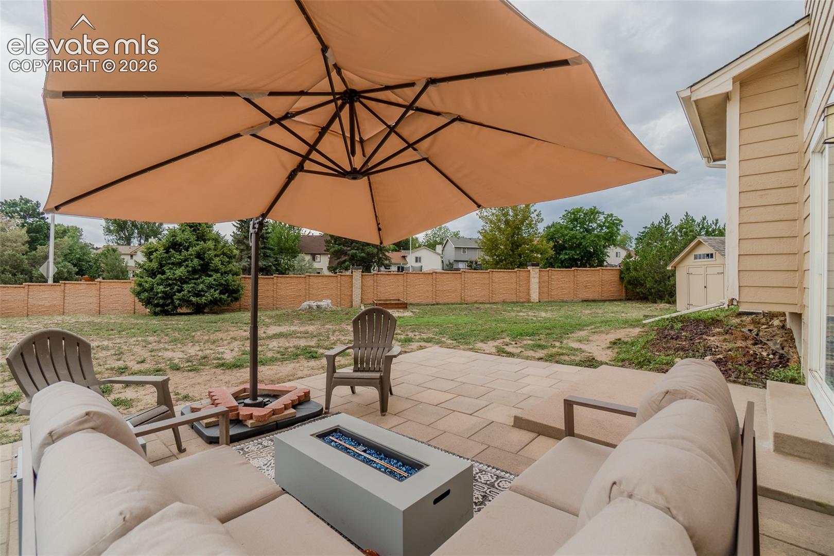 Patio with pavers, a built-in fire pit, and a separate storage shed