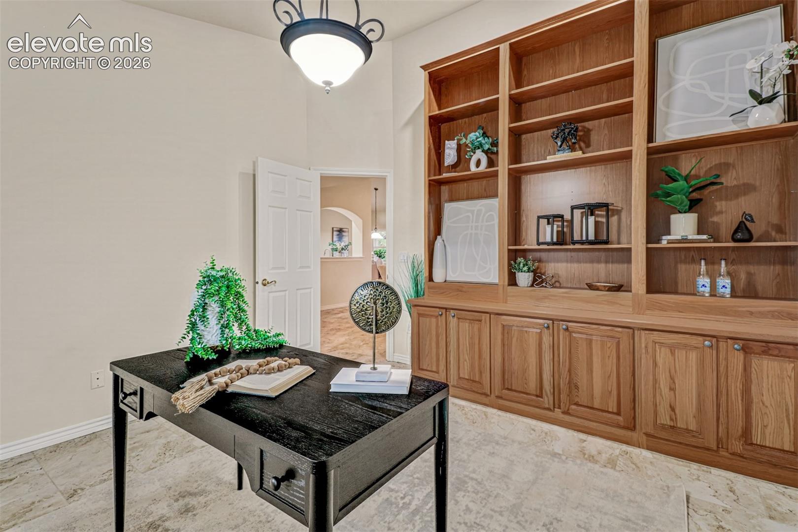 Custom floor-to-ceiling wooden built-in cabinetry featuring open shelving and lower storage, complemented by stone-finish flooring and a central pendant light fixture