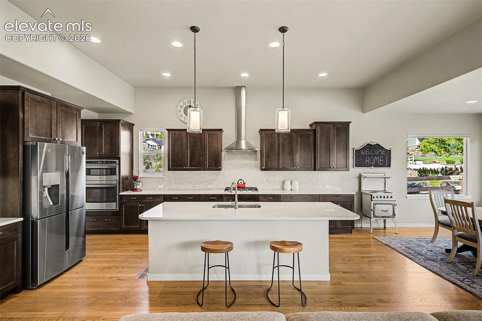 Gourmet kitchen features rich cabinetry, quartz countertops, premium stainless appliances, gas cooking, and a generous center island designed for both everyday living and entertaining.