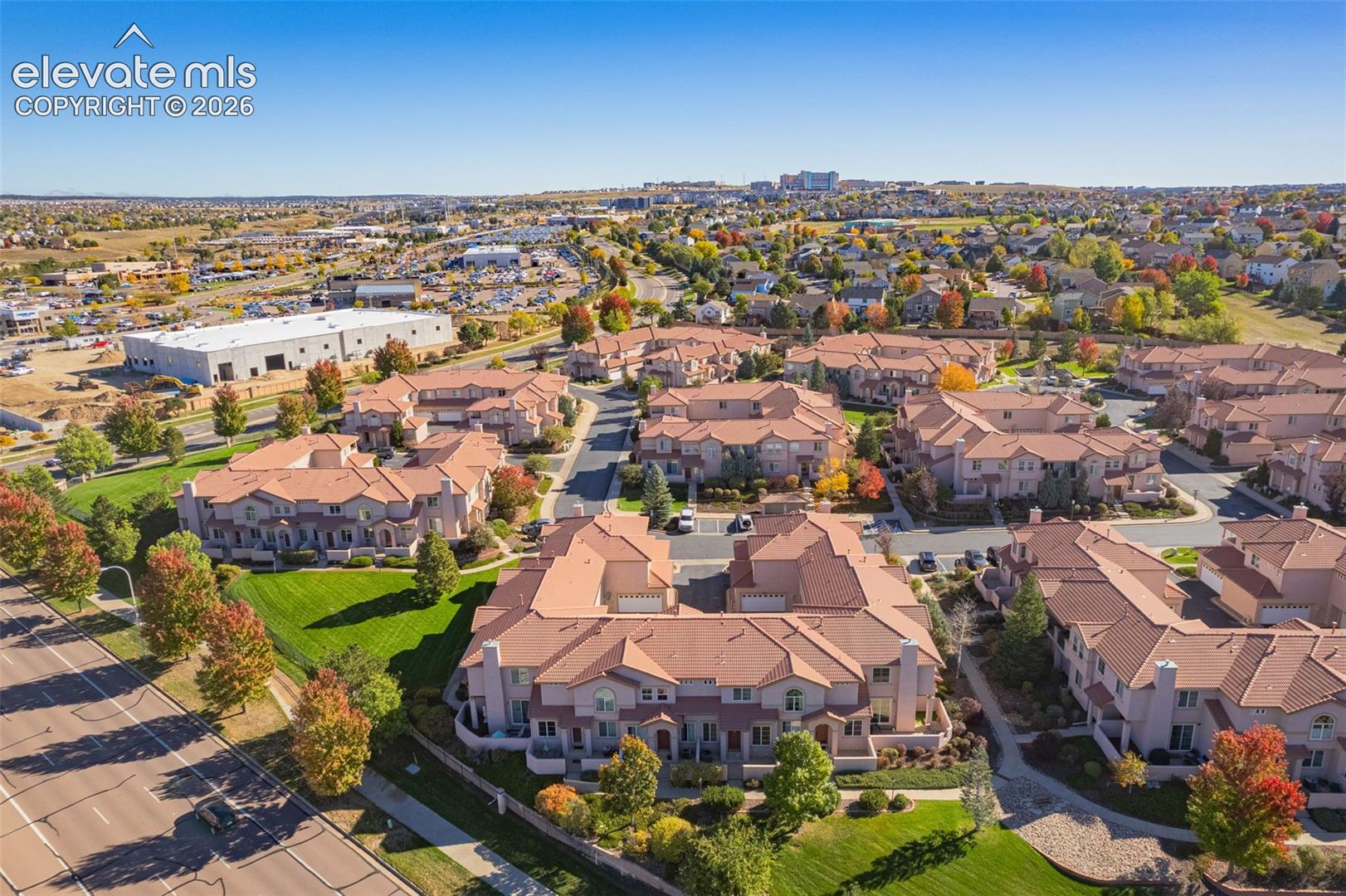 Aerial perspective of a multi-unit residential community featuring terracotta-style roofing, stucco siding, and manicured green spaces