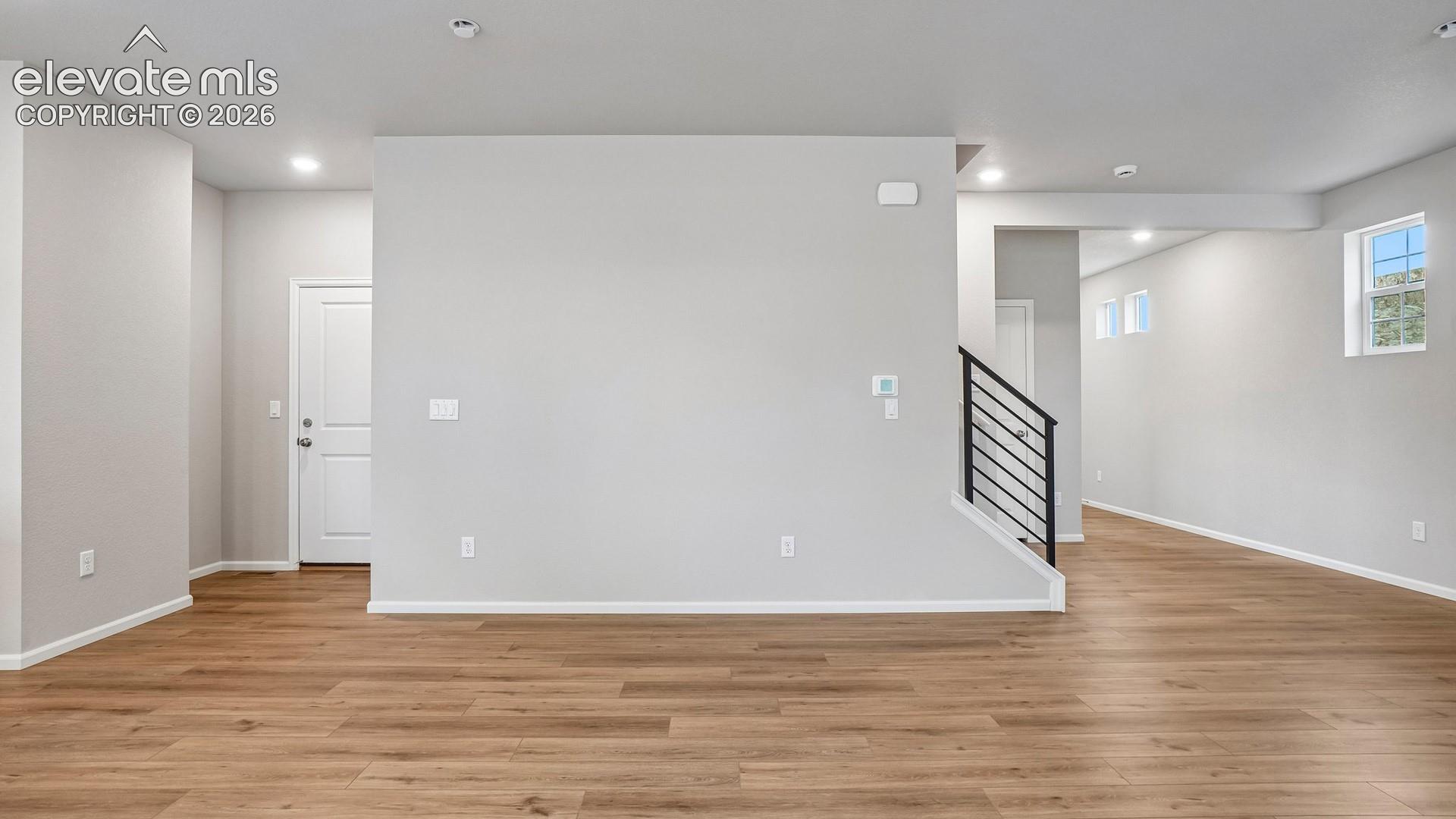Wood-finish flooring, recessed lighting, white interior doors, and a modern stair railing with black balusters
*photos of a model home*