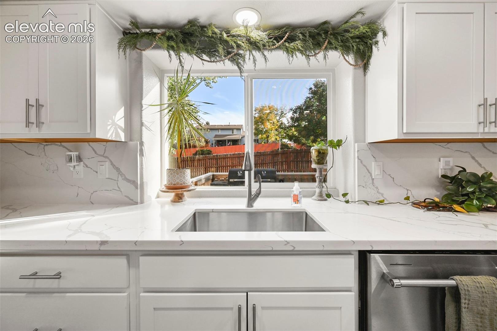 White shaker cabinetry with modern hardware, stainless steel undermount sink with a gooseneck faucet, and white countertops with a subtle gray veining