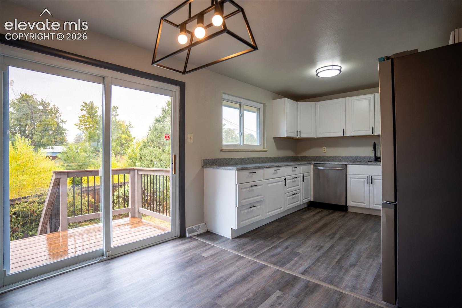 Kitchen featuring white cabinetry, stone-finish countertops, stainless steel dishwasher, wood-finish flooring, and geometric pendant lighting