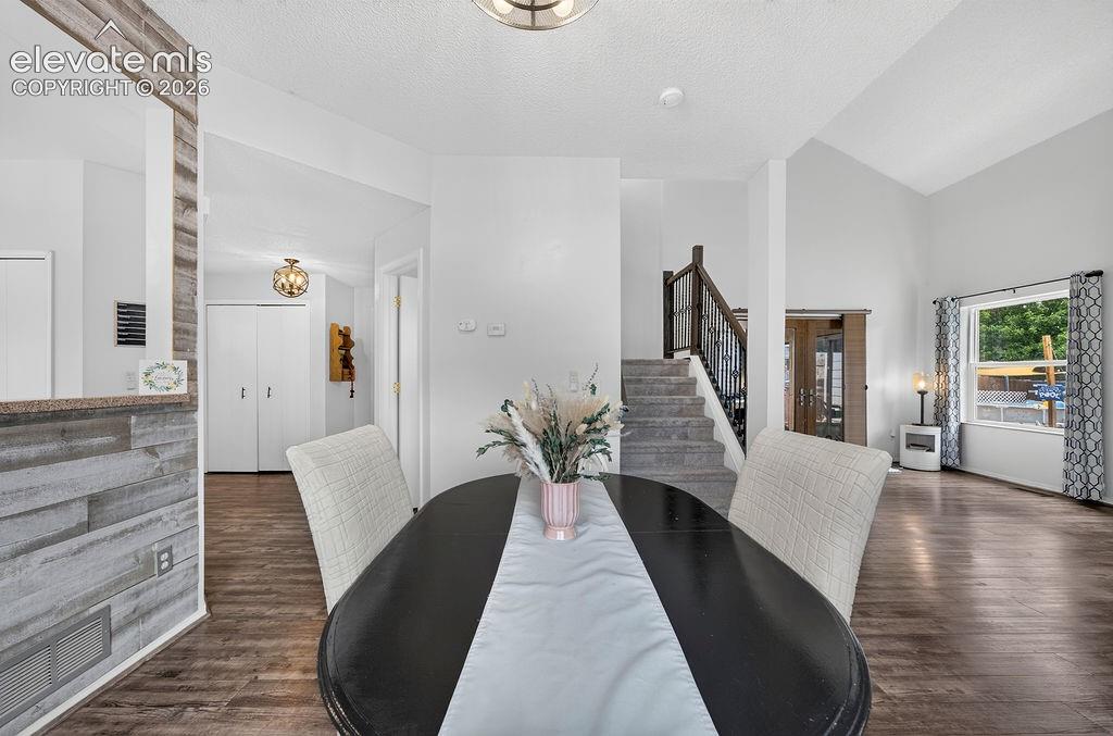 Vaulted ceiling, wood-finish flooring, staircase with wrought iron balusters, recessed lighting, and a prominent window