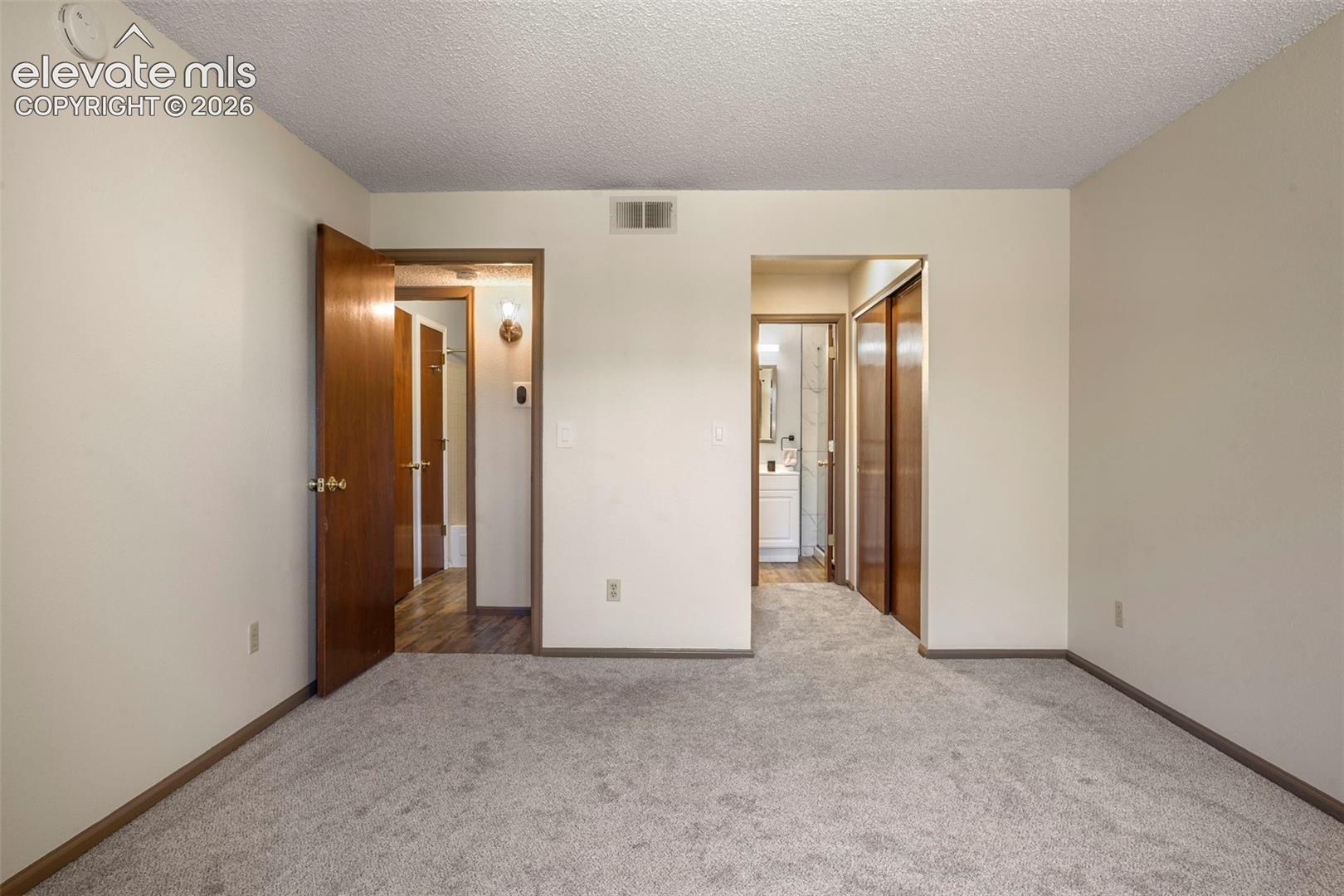 Unfurnished bedroom featuring a closet, a textured ceiling, and light colored carpet