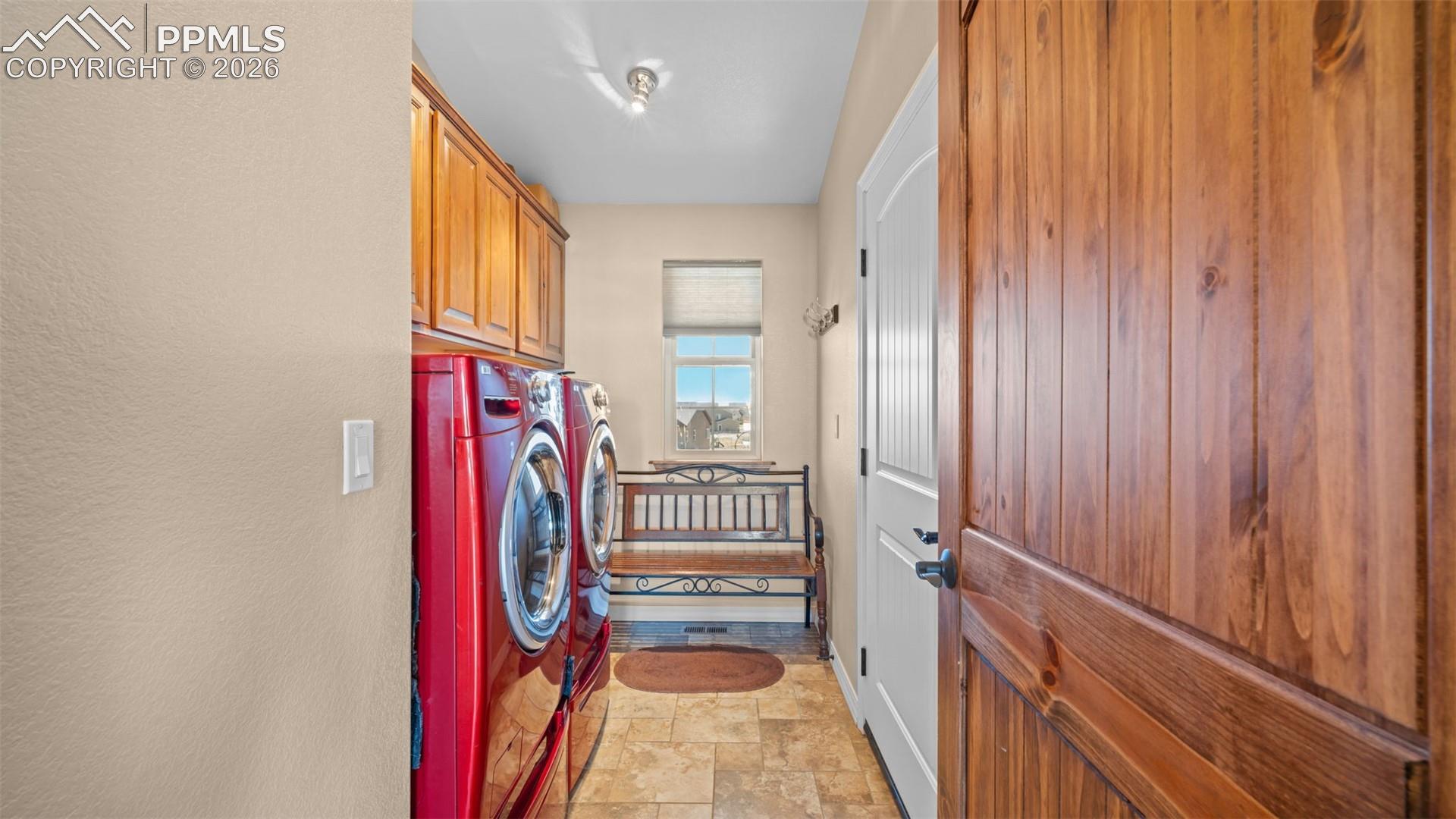 Laundry room featuring stone finish flooring, cabinet space, washer/dryer and laundry sink