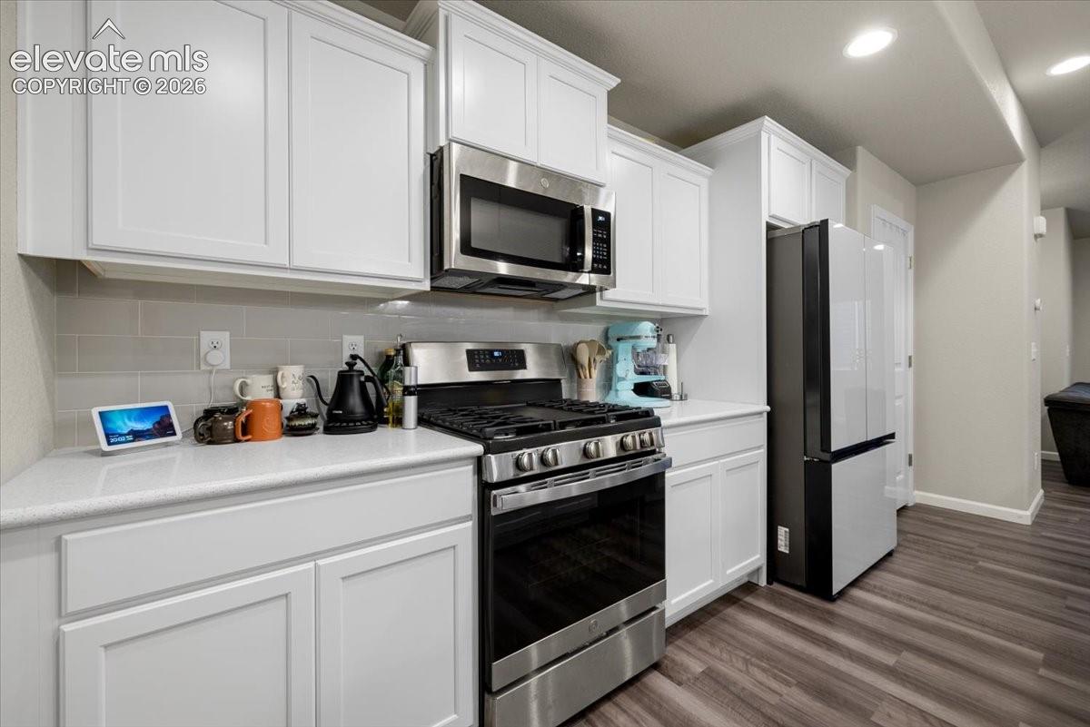 Kitchen featuring white cabinetry, light-toned countertops, a subway tile backsplash, and stainless steel appliances