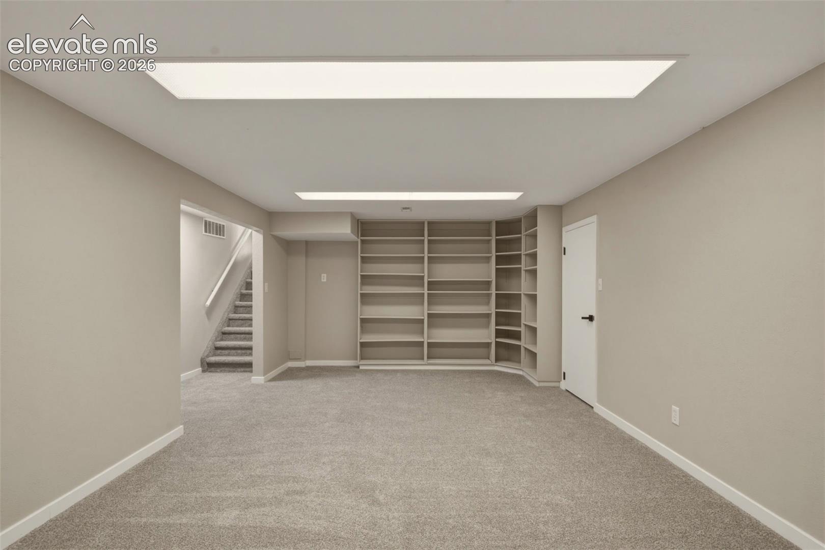 Recessed ceiling lighting, built-in shelving, gray carpeting, neutral wall paint, and white trim
