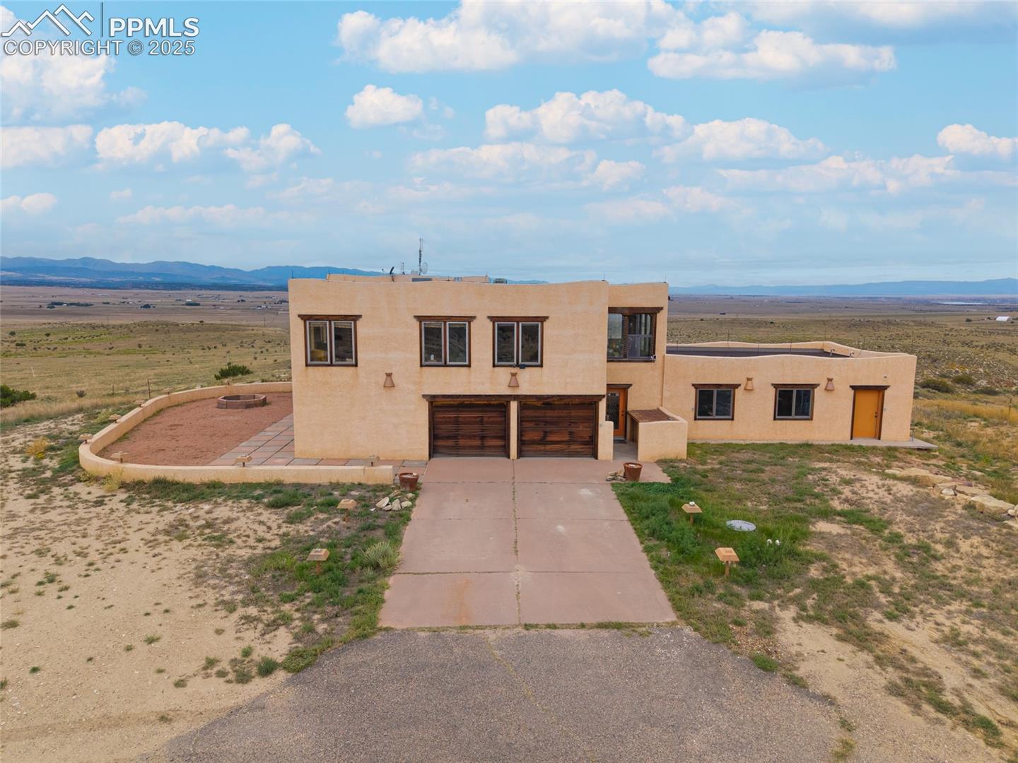 Pueblo revival-style home with stucco siding, concrete driveway, a mountain view, and an attached garage