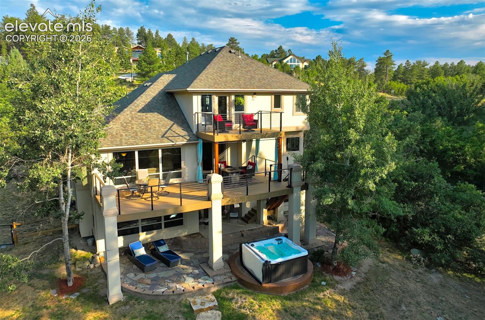 Multi-level exterior with two elevated decks, a ground-level patio, and an integrated hot tub
