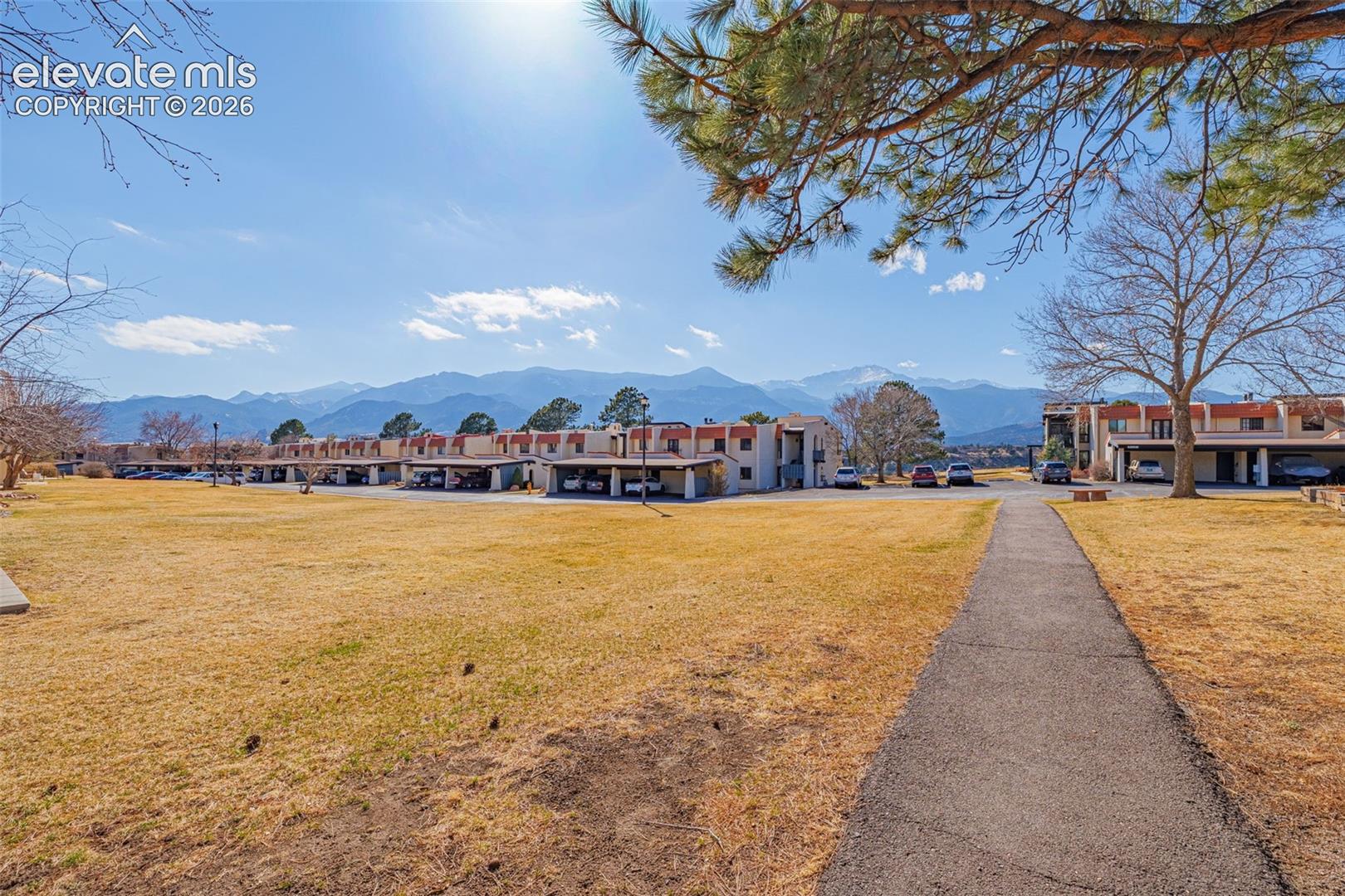 Community green space with a paved pathway, surrounded by multi-story residential structures with covered parking