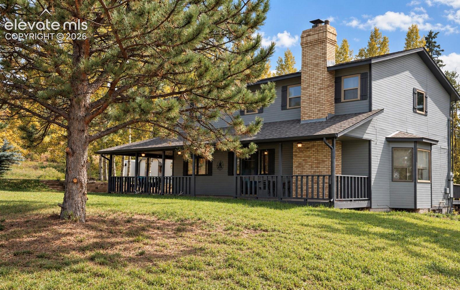 Charming two-story colonial with brick and board-and-batten siding, featuring a covered front porch with railings, gable roofline, and brick chimney