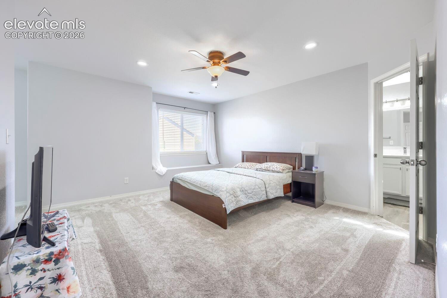 Neutral-toned carpeted flooring, recessed lighting, ceiling fan with integrated light fixture, and window with built-in ledge