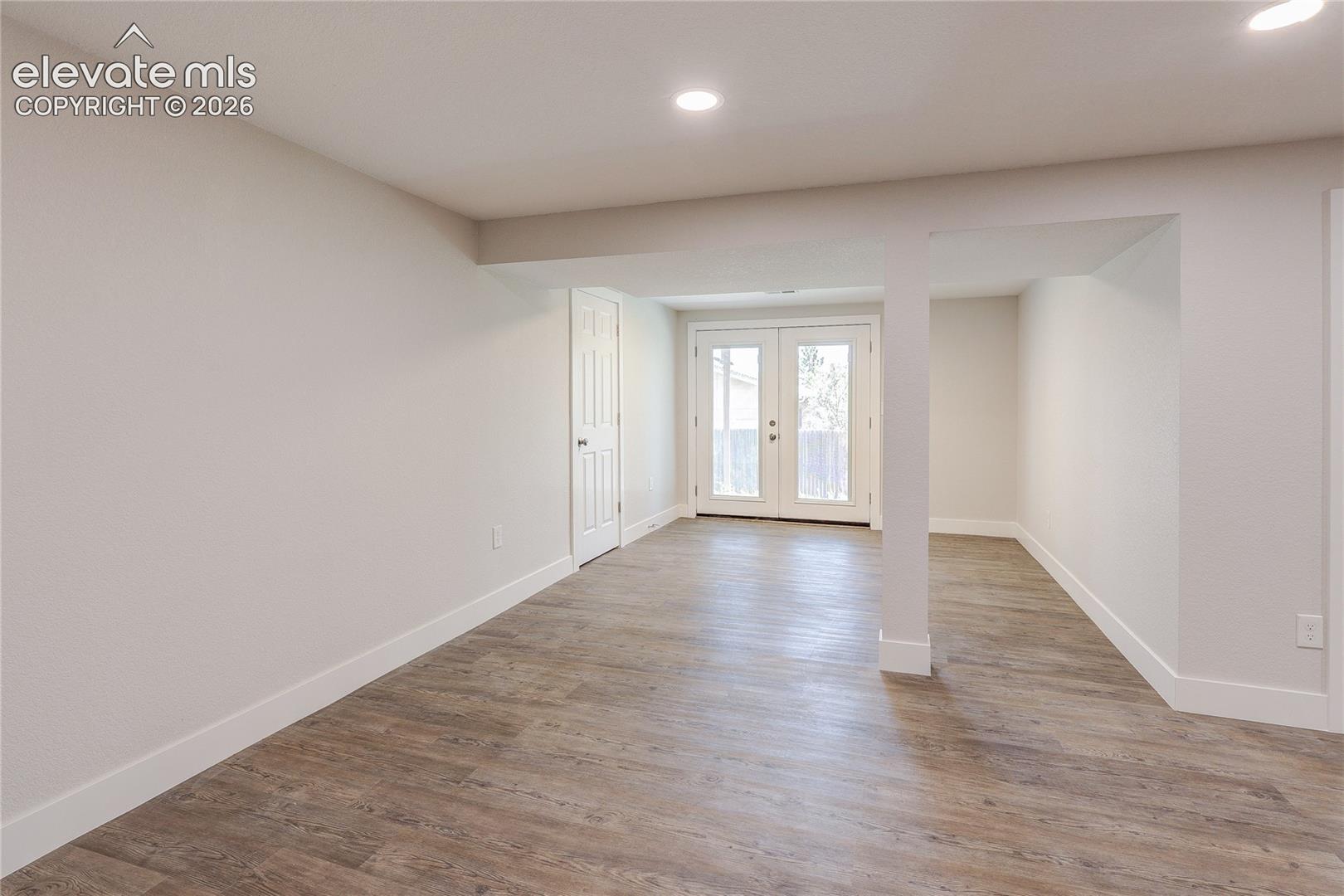 Neutral-toned interior featuring wood-finish flooring, recessed lighting, and double glass-paned doors
