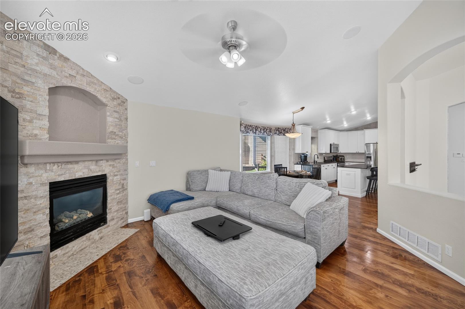 Living area featuring a floor-to-ceiling stacked stone fireplace with a floating mantel, wood-finish flooring, and recessed ceiling lighting