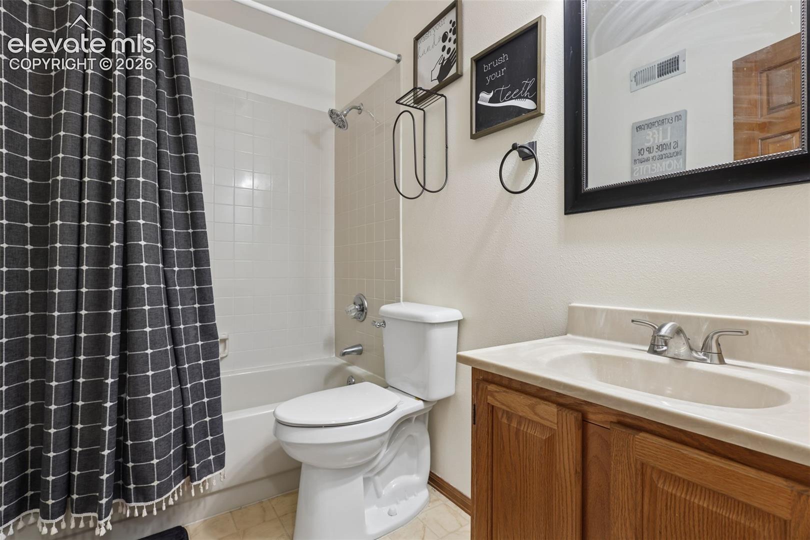 Tub and shower combination with a tile surround, single vanity with an integrated sink, and an undermount cabinet