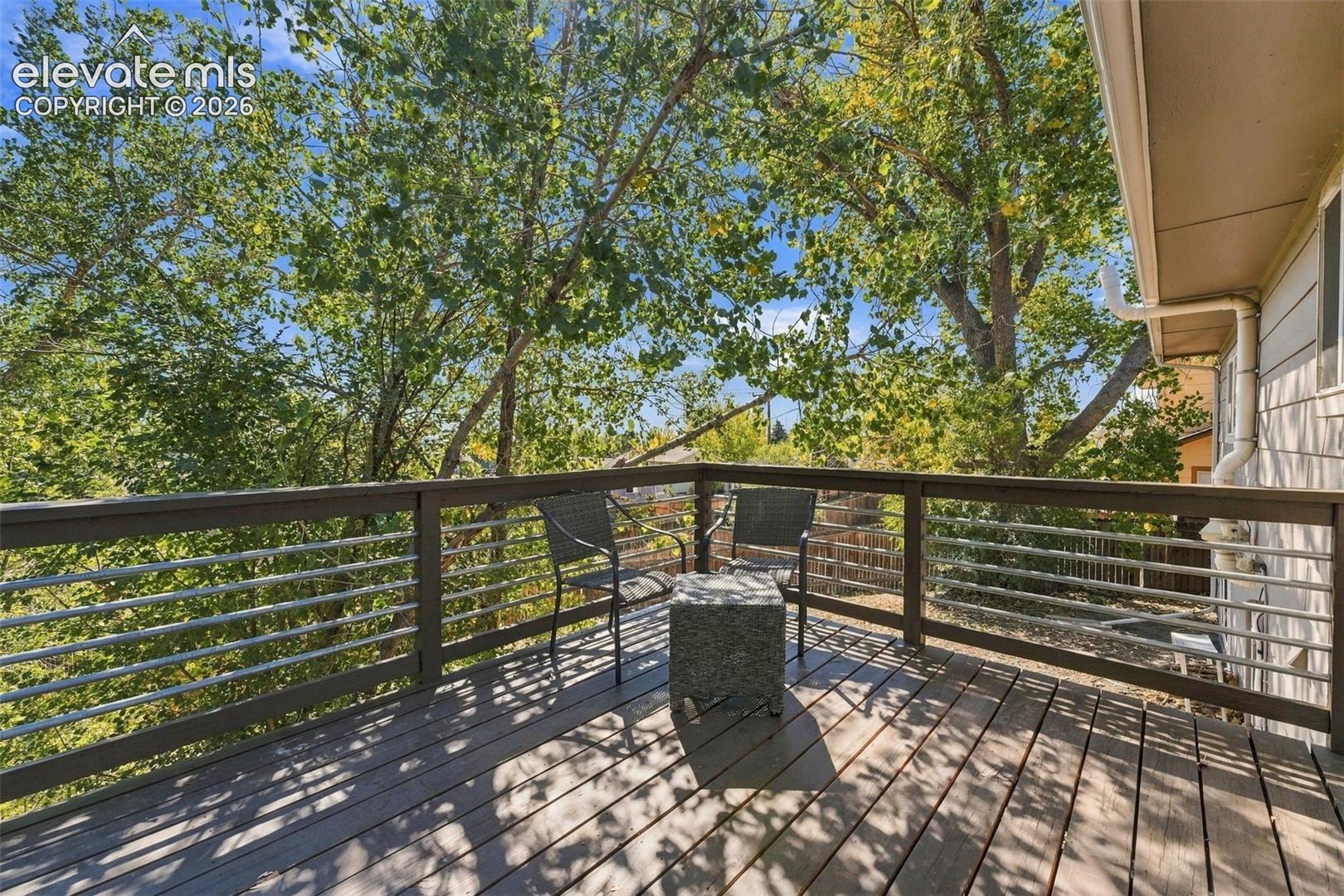 Outdoor deck featuring composite decking, a horizontal cable railing system, and mature trees