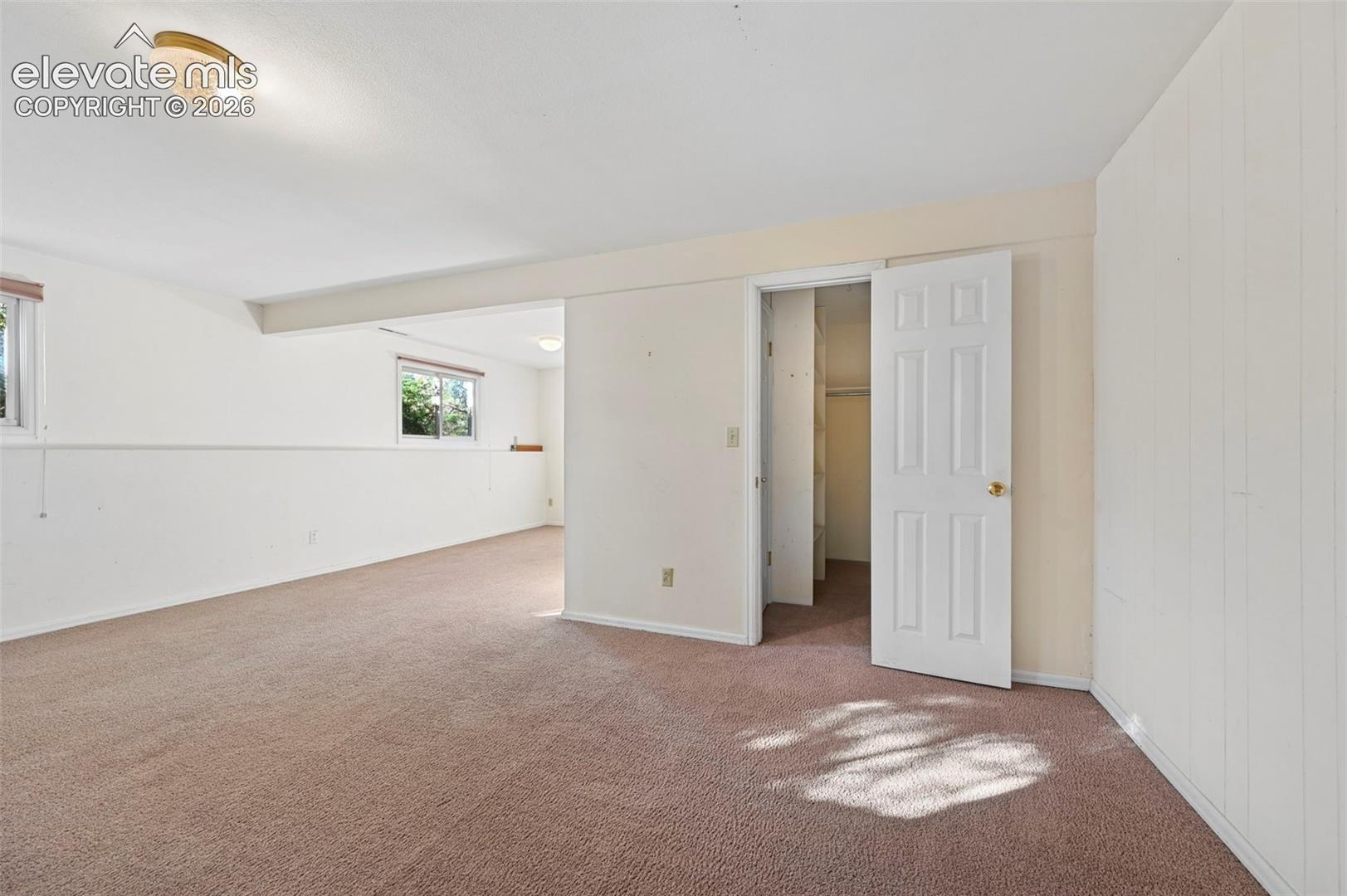 Carpeted interior space with white walls, multiple windows, and a flush mount ceiling light fixture