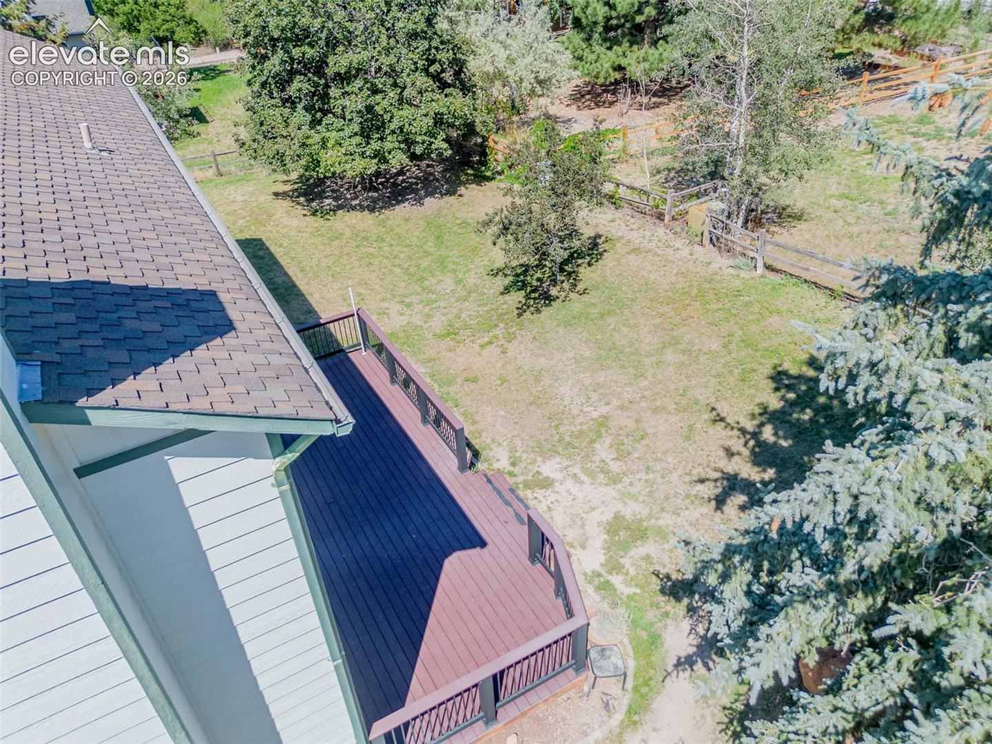 Expansive outdoor deck with dark railing, composite decking, and a shingle roofline