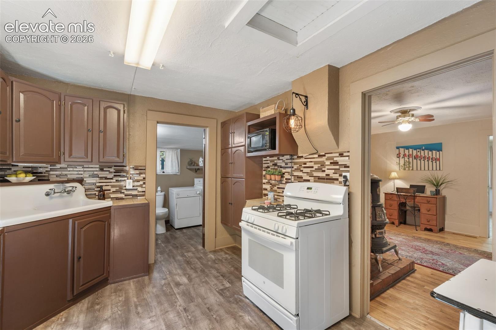 Kitchen featuring wood-finish flooring, brown cabinetry, and a multi-toned tile backsplash