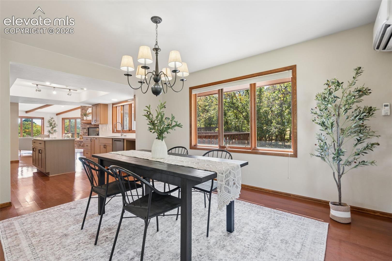 Hardwood-style flooring, large windows with natural wood trim, open concept design, recessed lighting, and a multi-light chandelier