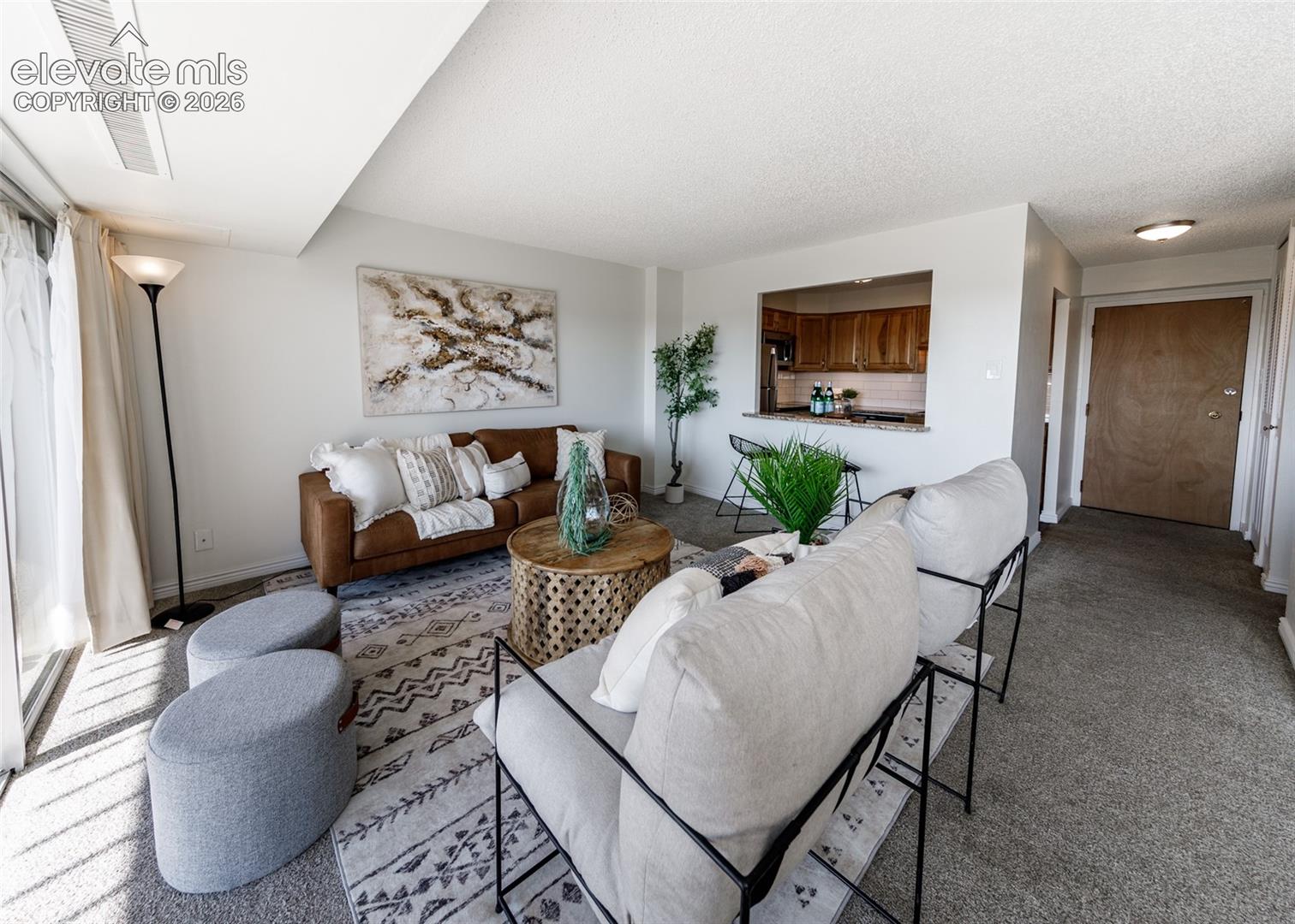 Living area featuring wall-to-wall carpeting and a pass-through opening to the kitchen