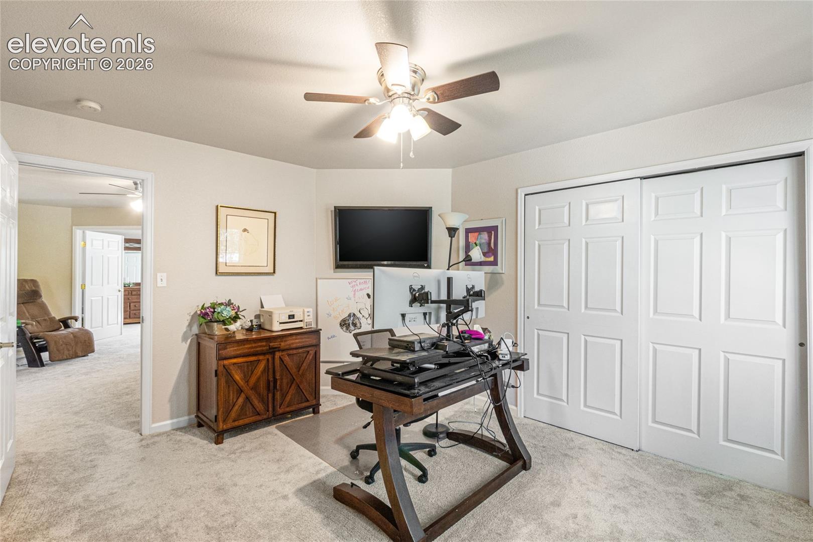 Room featuring neutral carpeting, a ceiling fan with integrated lighting, and white six-panel sliding closet doors
