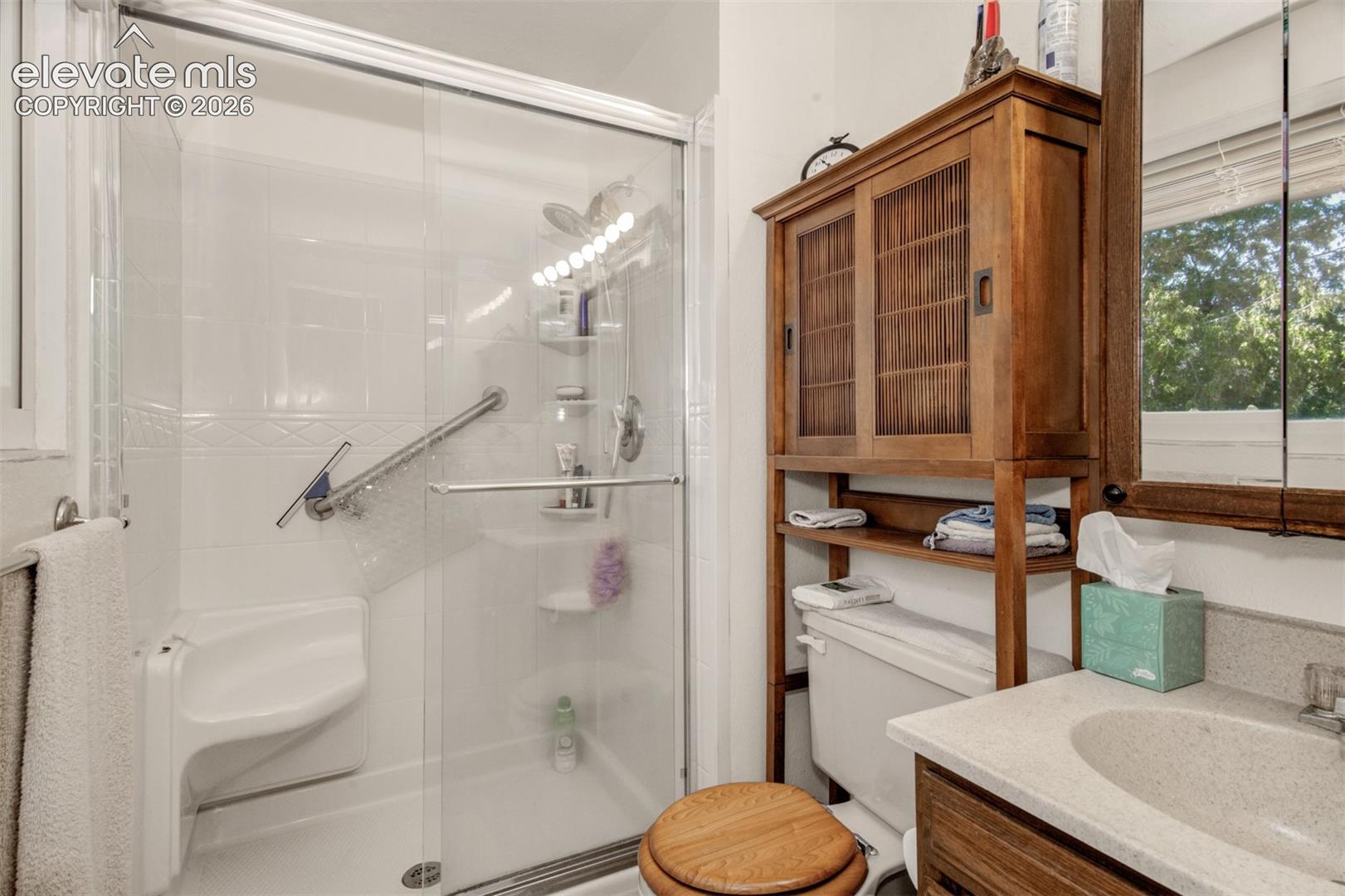 Spa-inspired bathroom featuring a frameless glass-enclosed shower with integrated shelving, dual vanity with vessel sink and quartz countertop, and wood-finish cabinetry