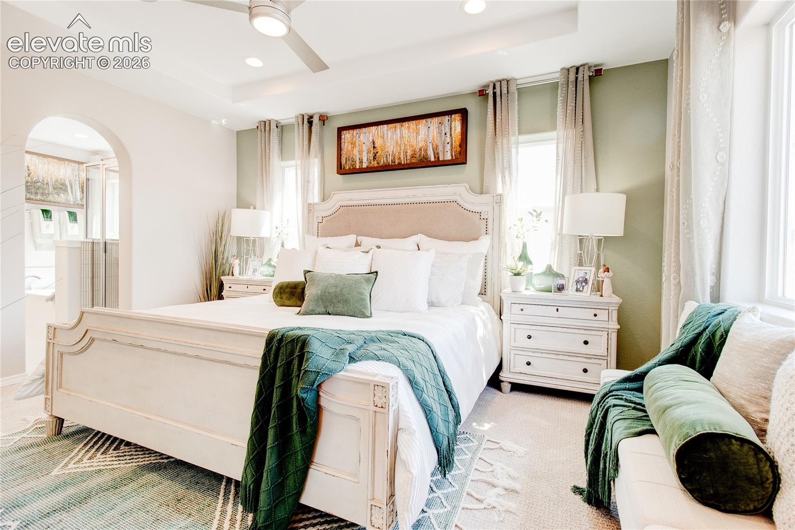 Tray ceiling featuring recessed lighting and a ceiling fan, arched doorway, and neutral wall tones