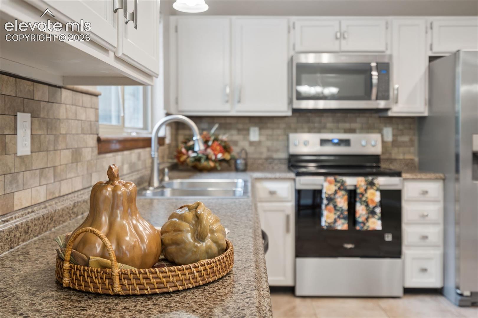 Kitchen has solid surface countertops w/a tiled backsplash