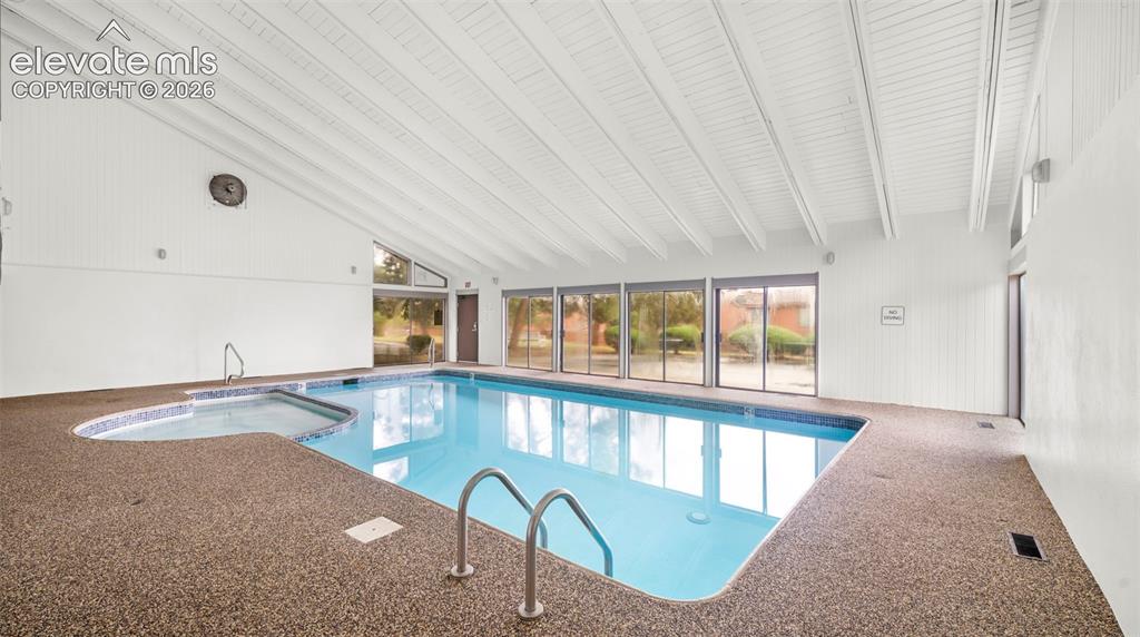 Indoor swimming pool with an integrated spa, surrounded by stone-aggregate decking