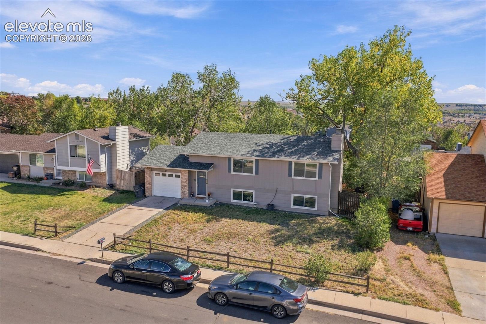 Split-level residence featuring a two-car attached garage, a paved driveway, and a front entrance with a porch