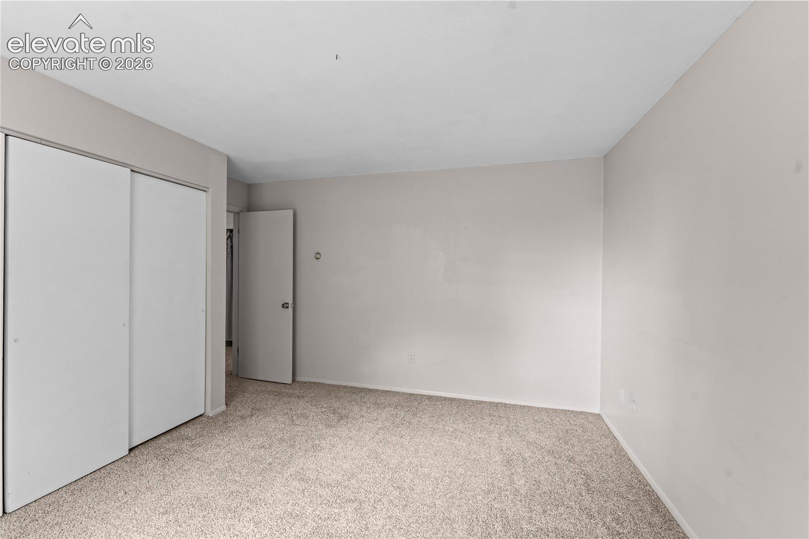 Neutral-toned interior featuring wall-to-wall carpeting, sliding closet doors, and a swing-style interior door