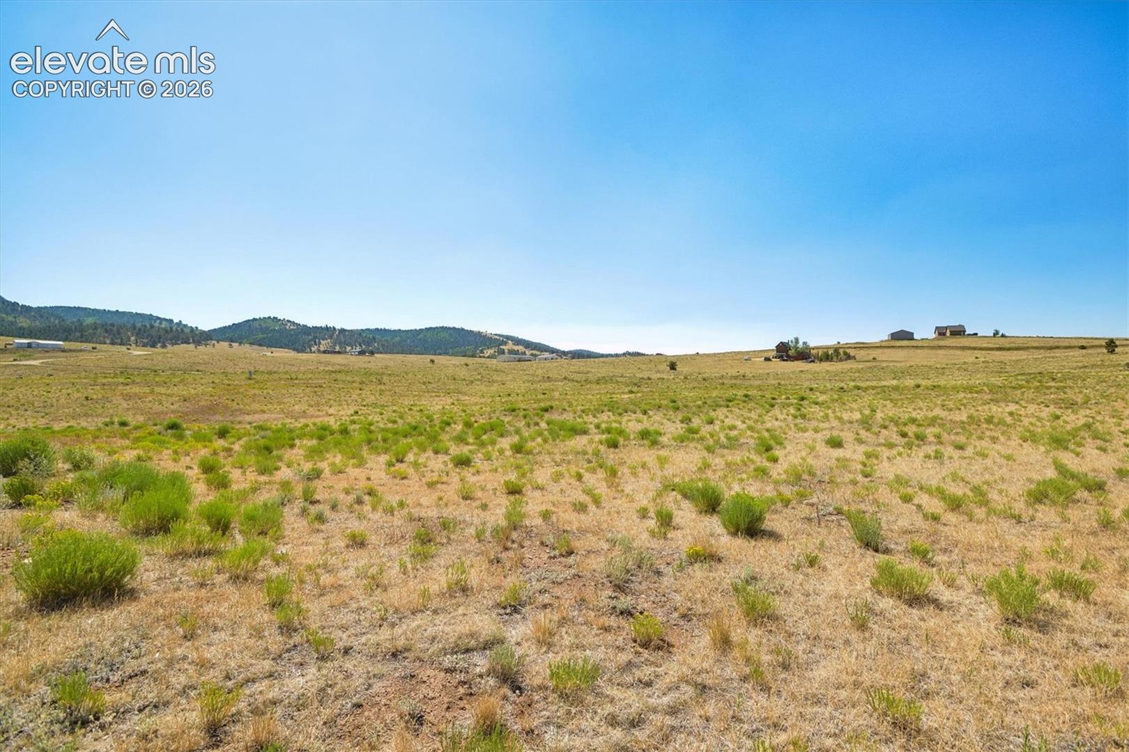 Expansive land parcel featuring natural grasses and distant rolling hills