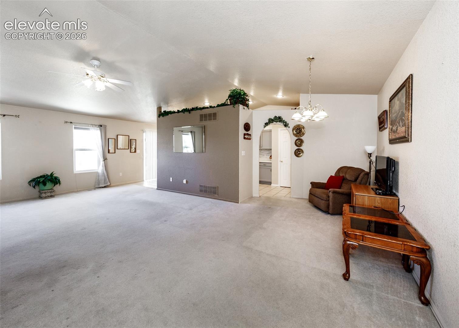 Vaulted ceilings with recessed lighting, an architectural archway, a central partition wall, and multi-light chandelier