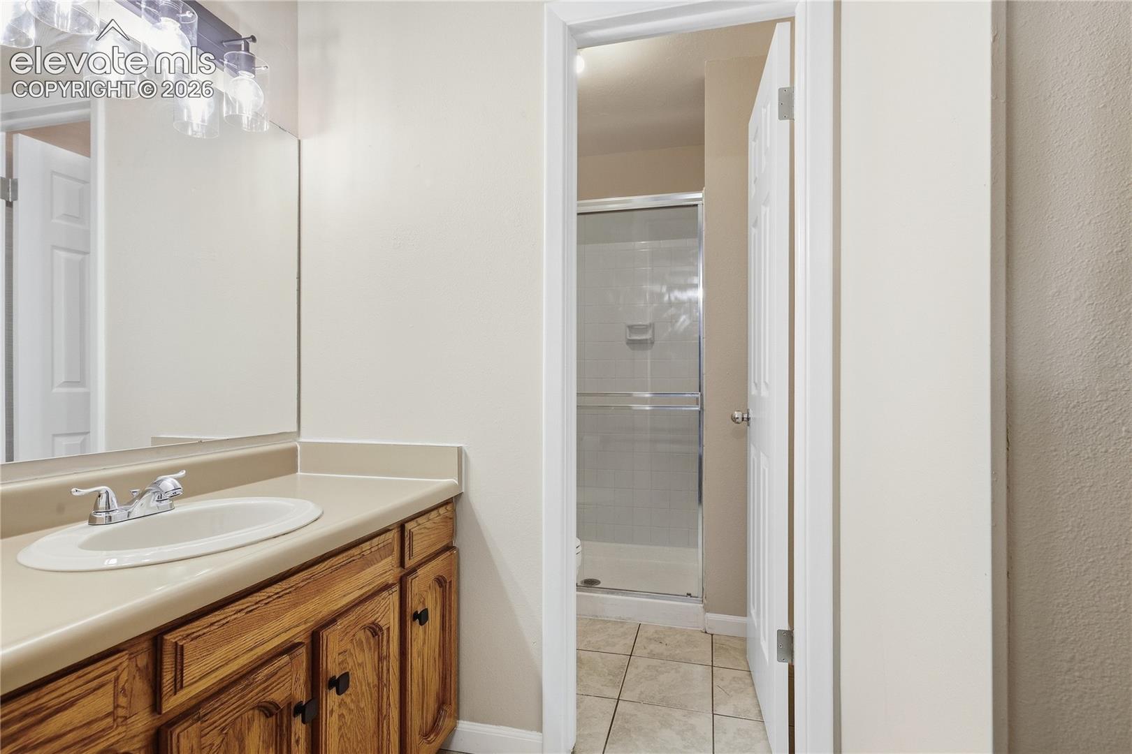 Bathroom vanity with wood-finish cabinetry, integrated sink, and wall-mounted light fixture