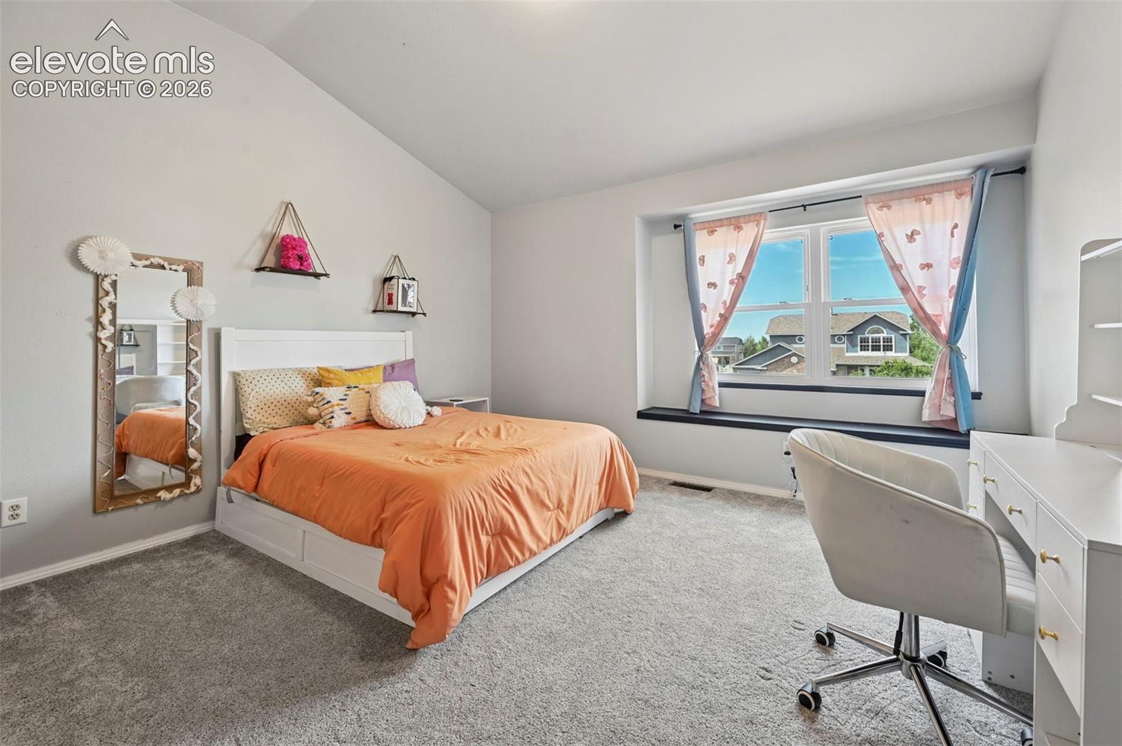 Spacious room with a vaulted ceiling and light gray walls