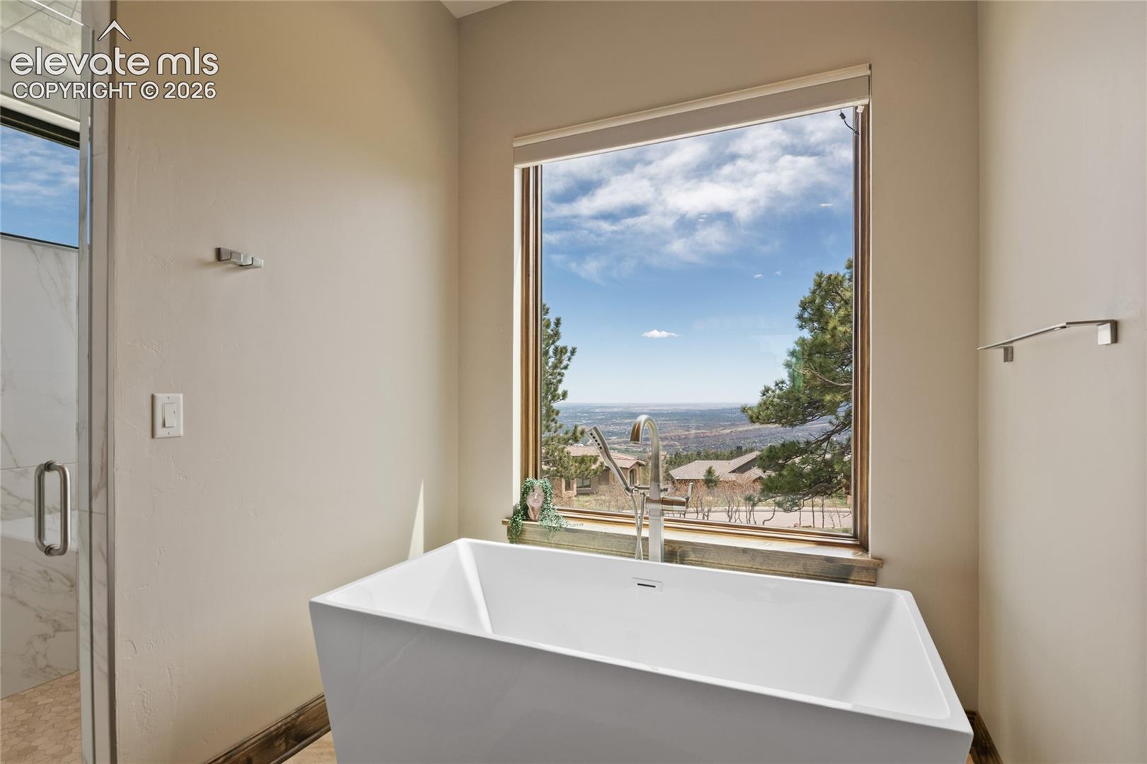 Soak in the skyline. Deep freestanding soaking tub positioned at a private picture window with sweeping views of the valley and city lights below.