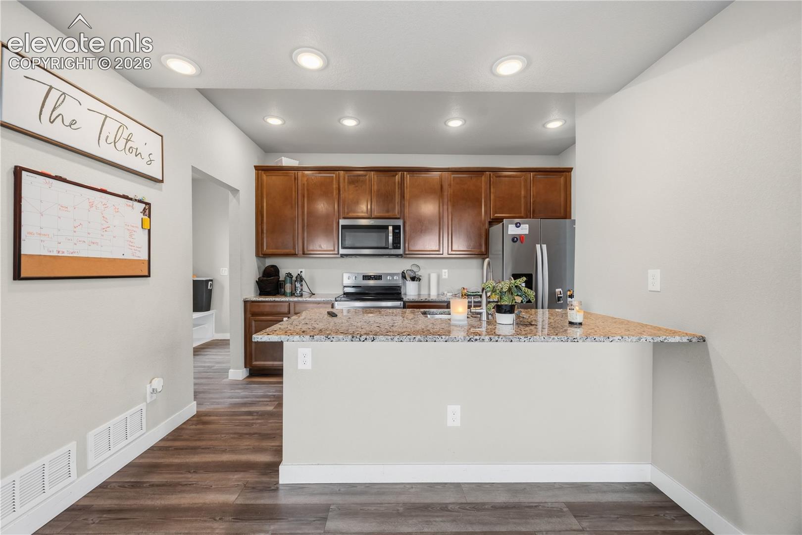 The Island Kitchen features recessed lighting, a breakfast bar, wood cabinetry with granite countertops, and stainless steel appliances.