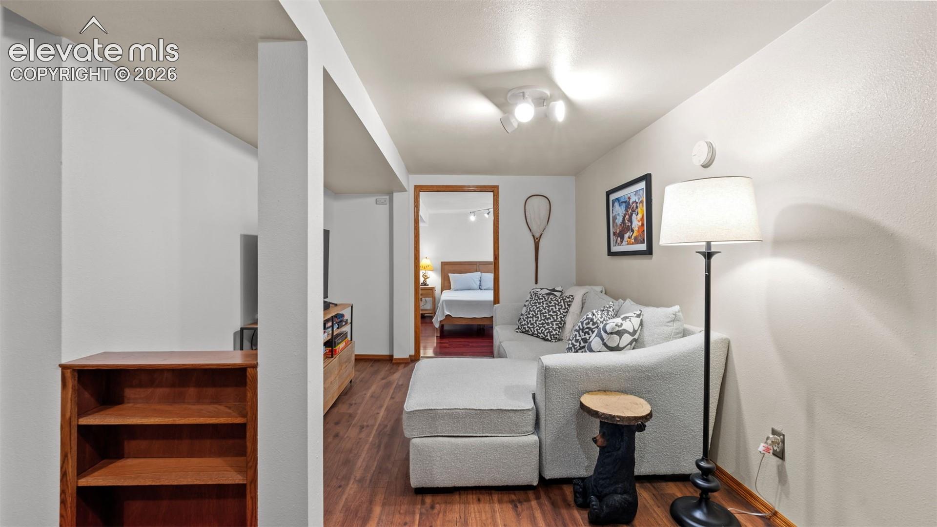 Wood-finish flooring, neutral wall tones, built-in shelving, and multi-directional track lighting