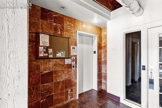 Corridor with tile walls and elevator