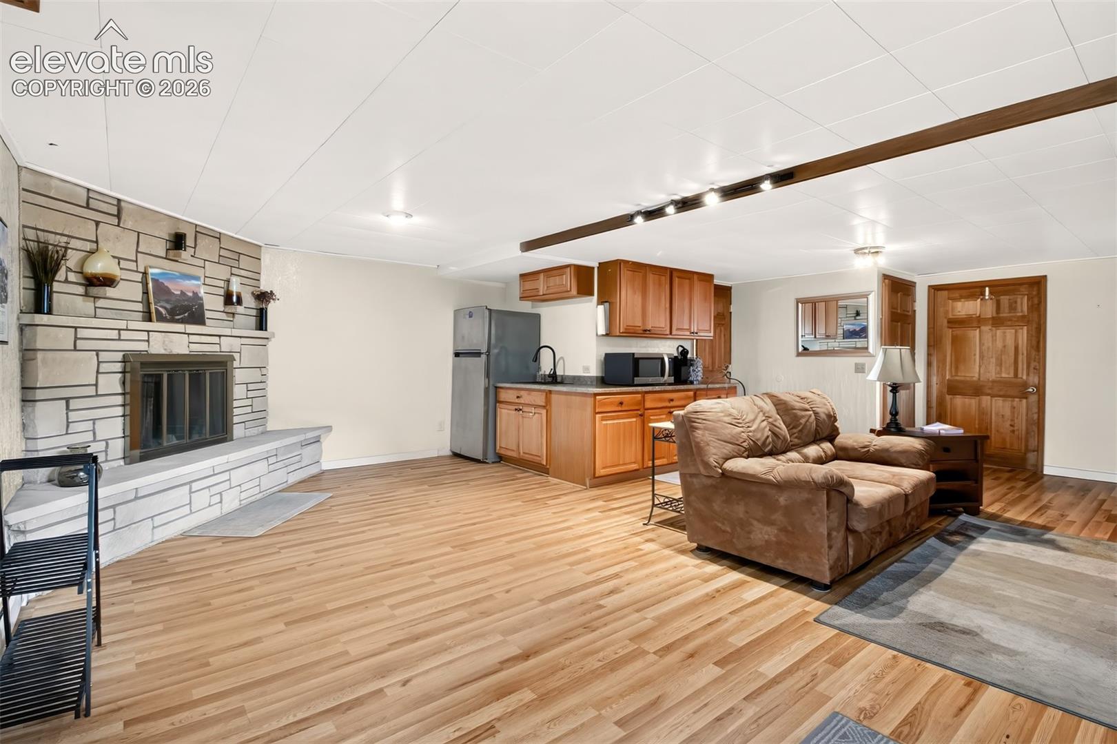 A view of the basement living room with fireplace andkitchenette with laminate vinyl wood floors