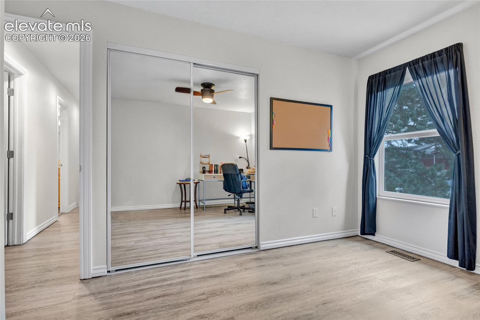 Bedroom featuring wood-finish flooring, a double window, and white trim