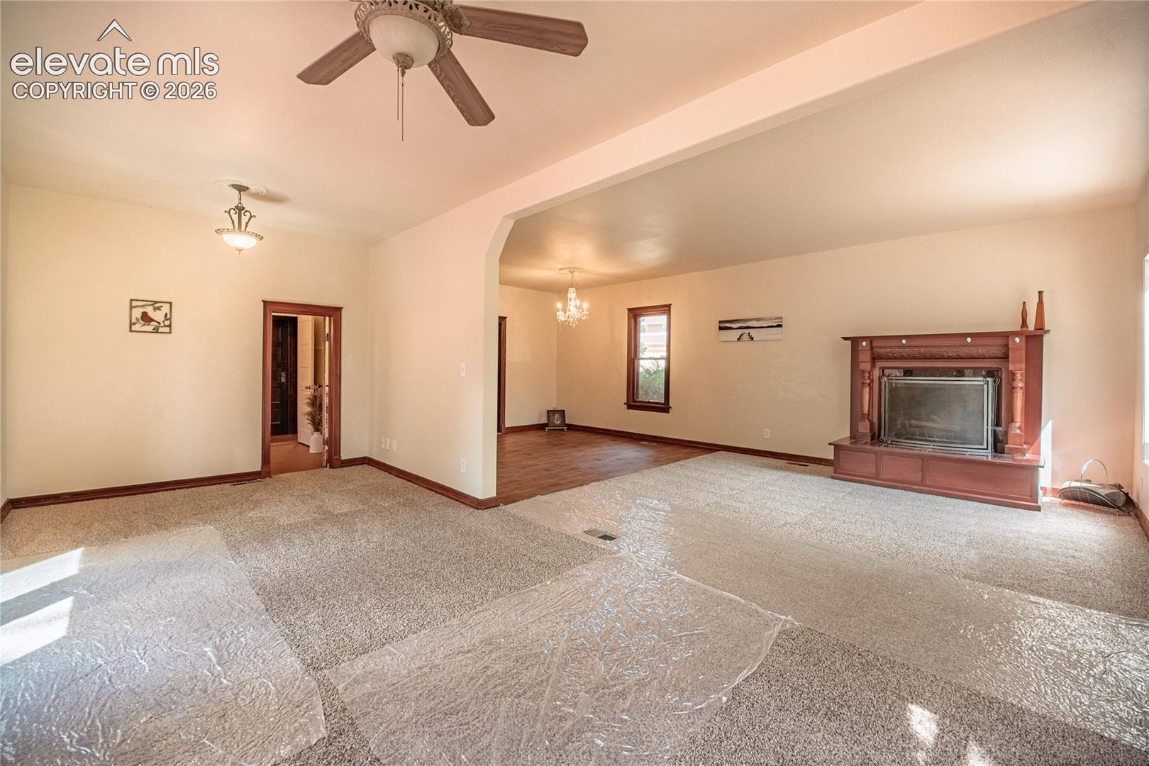 Spacious living area featuring a decorative fireplace, carpeted flooring, and a ceiling fan
