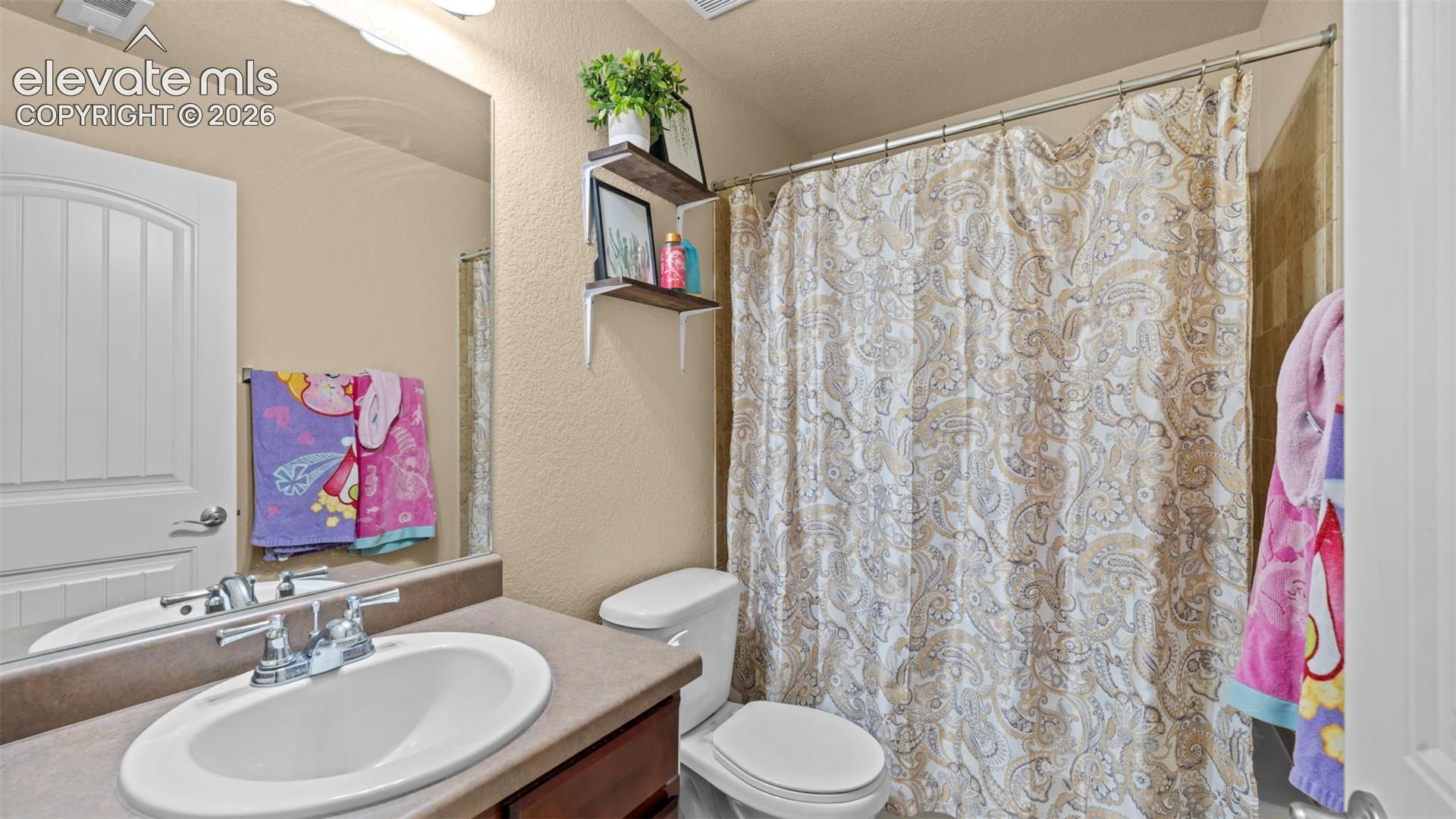 Bathroom featuring a single vanity with an integrated sink, a large wall mirror, and a shower/tub combination with tiled surround