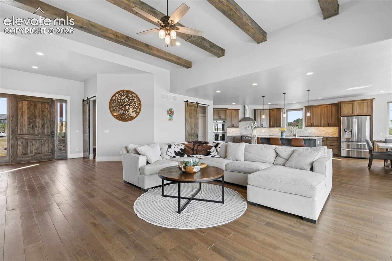 Vaulted ceiling with exposed wood beams, wood-finish flooring, recessed lighting, and a ceiling fan